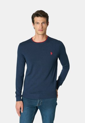 Maglione blu navy a maniche lunghe in tessuto a maglia morbida, con scollo a righe rosse e piccolo logo rosso sul petto. Vestibilità casual.
