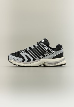 Baskets de sport noires et grises avec dessus en mesh et synthétique, semelle amortie et détails réfléchissants, présentées sur un fond uni.