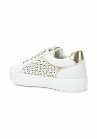 Zapatilla blanca con diseño perforado en los laterales, detalles metálicos dorados en el talón y los cordones, y suela de goma blanca.