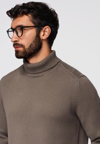 Brązowy sweter z golfem, wykonany na drutach, z prążkowanym kołnierzem, charakteryzujący się dopasowanym krojem i średnią grubością, prezentujący fakturowany materiał.