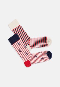 Gestreifte Socken in einer Mischung aus Rot, Weiß und Marineblau. Eine Socke hat Anker-Muster; die andere hat abwechselnde Streifen. Weicher Stoff.