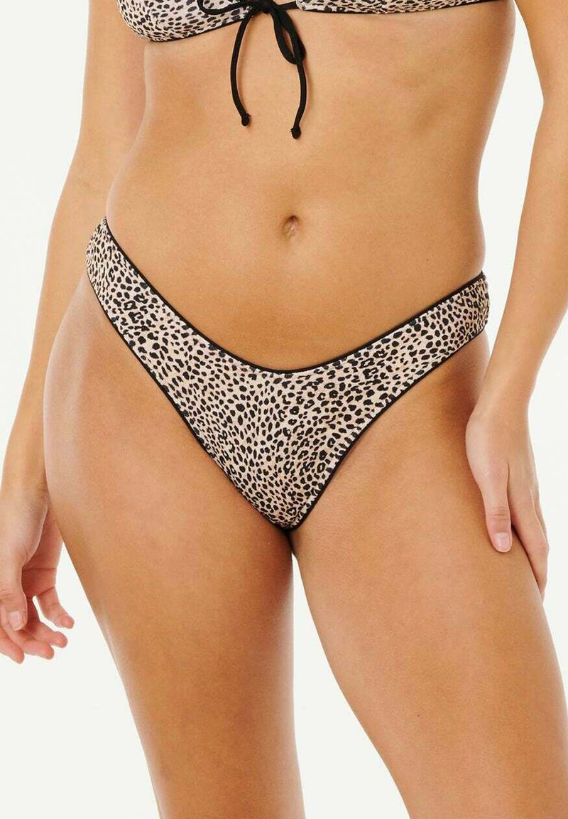 Kvinde iført leopardmønstret bikinibund med sort kant, der viser mellemgulvet og hænderne ved siderne mod en ensfarvet baggrund.