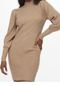 Robe en maille marron clair avec côtes verticales, col montant et manches bouffantes. Présente une silhouette ajustée et un ourlet à hauteur des genoux.