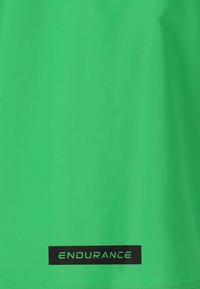 T-shirt de sport vert vif avec une texture lisse et une étiquette noire portant le mot "ENDURANCE" au bas.