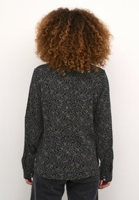 Chemise à manches longues avec un motif floral bleu marine dans des tons de vert et de bleu. Tissu doux et léger, avec des poignets à boutons et un ourlet arrondi.