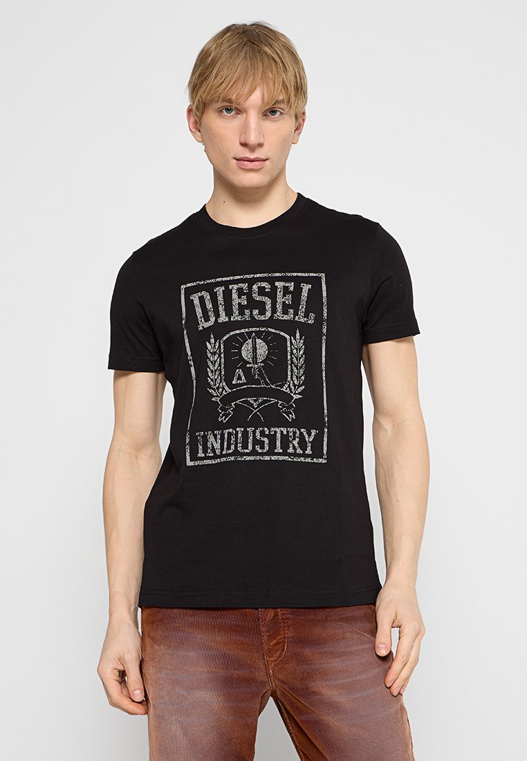 T-shirt en coton noir avec un imprimé graphique gris usé portant la mention "DIESEL INDUSTRY". Manches courtes, col rond, coupe ajustée.