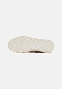 Weiße Gummisohle eines Schuhs mit strukturiertem Muster aus Rautenformen und einer glatten Kante, entwickelt für Griffigkeit und Haltbarkeit.