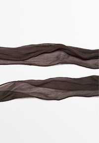 Nastro opaco di un marrone scuro, leggermente trasparente con una superficie ondulata e strutturata. I bordi sono a forma di scallop, mostrando una leggera lucentezza.