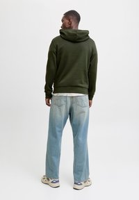 Olive green hoodie with a drawstring hood, paired with light blue wide-leg jeans. Notable features include a smooth texture and casual fit.