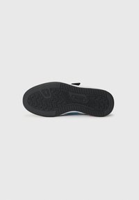 Semelle de chaussure en caoutchouc noir avec un motif texturé ; bords arrondis et logo ; talon renforcé pour le soutien ; partie supérieure principalement blanche.