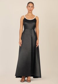 Schwarzes Satin-Abendkleid mit tailliertem Oberteil und bodenlangem Rock. Weißes, mit Perlen besetztes Detail am Ausschnitt, minimalistisches Design, glatte Textur.