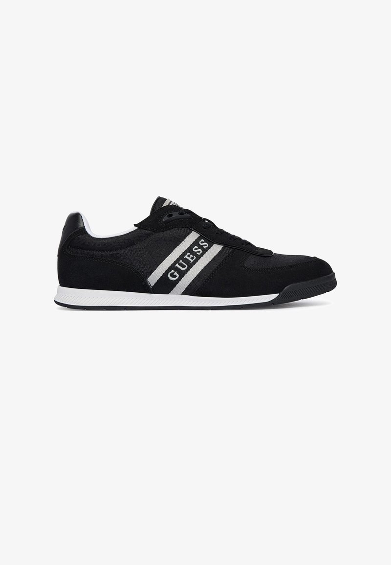 Baskets basses noires avec semelle blanche et rayures grises, avec le nom de la marque "GUESS" sur le côté.