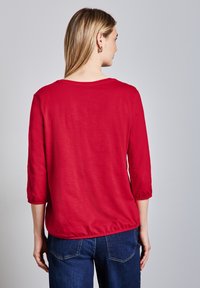 Rode shirt met driekwart mouwen, gemaakt van zachte stof met een relaxte pasvorm en een elastische zoom. Ontworpen met een ronde hals en een casual stijl.