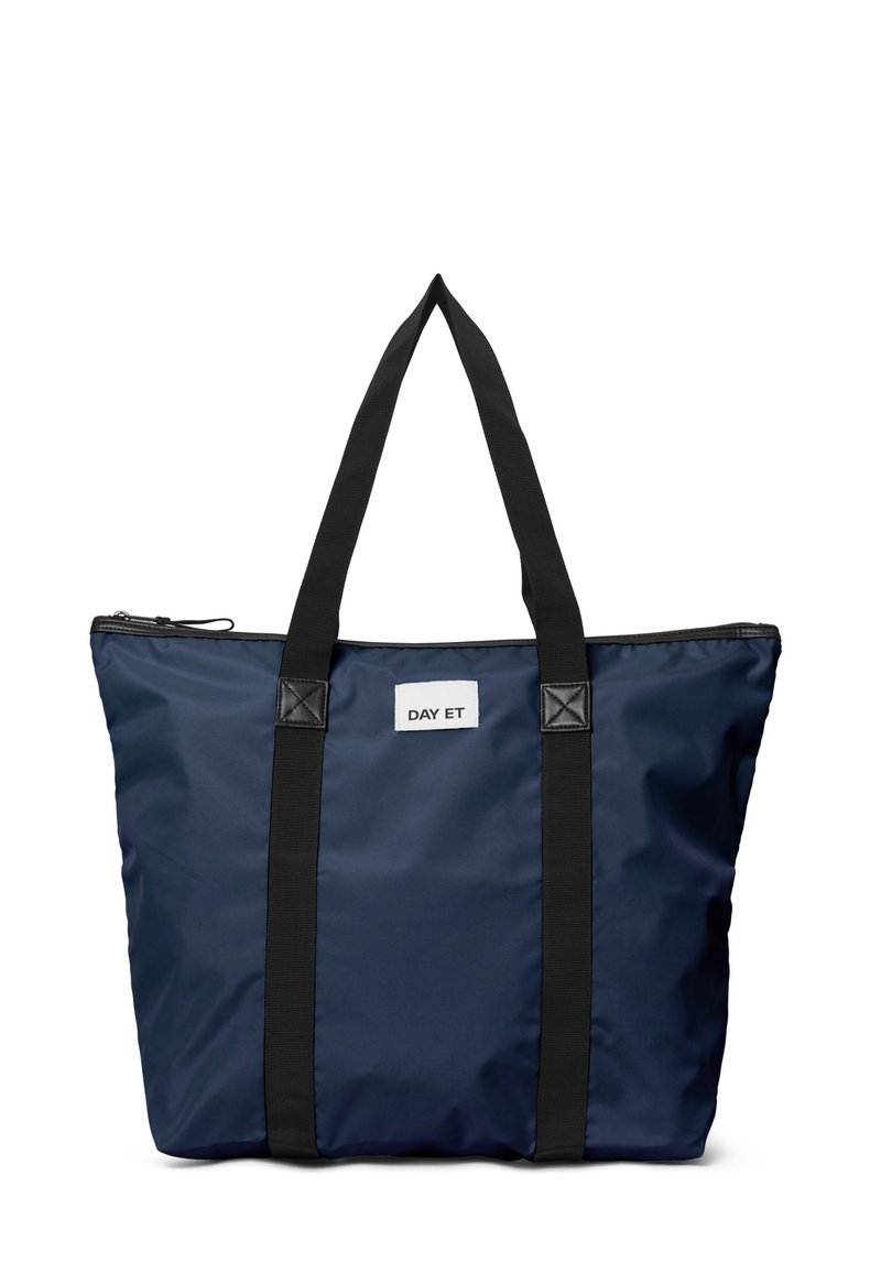 Borsa a tote navy con manici neri e zip, etichettata "DAY ET", progettata per l'uso quotidiano, che mostra un'estetica moderna e semplice.