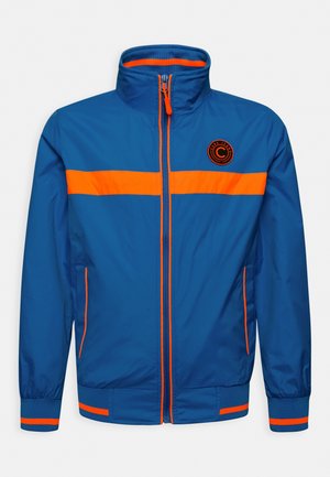 Chaqueta ligera azul con acentos naranjas, cierre de cremallera, cuello alto y puños elásticos. Presenta un logo en el lado izquierdo del pecho y rayas horizontales.