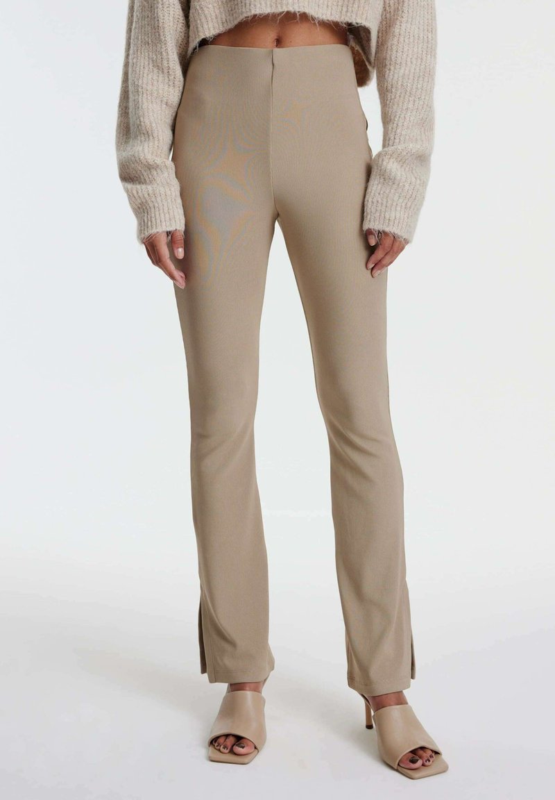 Beige, hoge taillebroek met zijsplitten aan de zoom, gemaakt van een soepele, rekbare stof, gecombineerd met lichtbeige open-toe hakken.