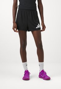 Mustad mustikas jämeda elastse vöökoha ja valge Adidas logo vasakul küljel. Koos valgete sokkide ja roosa jalatsiga.