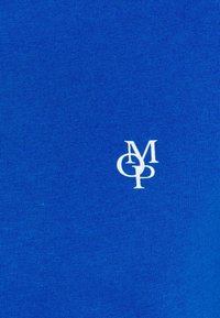 Blaues Baumwoll-T-Shirt mit glatter Textur, das ein kleines weißes Logo "MCP" auf der Brust trägt.