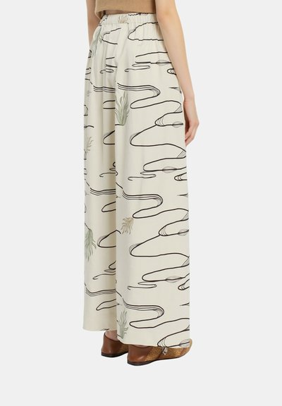 Pantaloni a gamba larga in tessuto beige chiaro, con linee astratte nere e accenti verdi. Vita elastica con una superficie liscia.