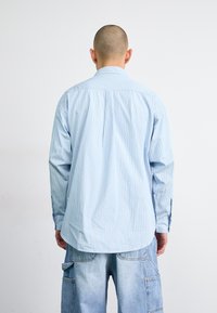 Lichtblauw overhemd met lange mouwen met verticale strepen, met knoopmanchetten en een iets getailleerde pasvorm, gecombineerd met lichtdenim cargobroek.