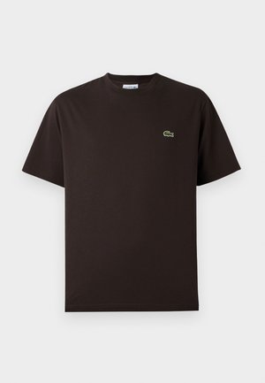 Brun kortermet T-skjorte laget av bomull. Har en subtil grønn brodert krokodillelogo på venstre bryst. Klassisk crew neck-design.
