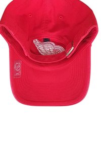 Red baseball cap with NHL logo sticker on brim and embroidered winged wheel logo inside the cap's inner band.