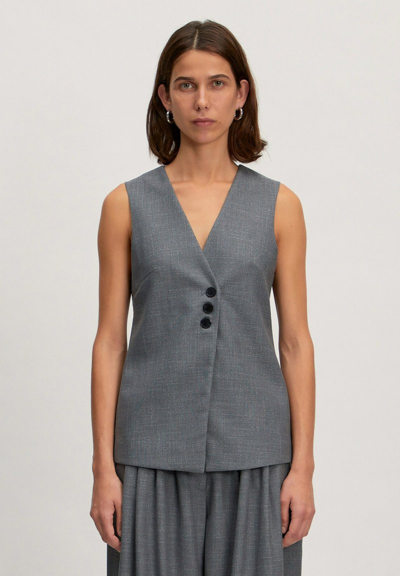 Grijze geweven vest met een V-hals, mouwloos ontwerp en drie zwarte knopen aan de voorkant. Glad textuur, getailleerde pasvorm en minimalistische stijl.