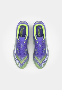 Paarse voetbalschoenen met een textuurpatroon, voorzien van groene en witte accenten, F50-logo en vetersluiting voor een veilige pasvorm.