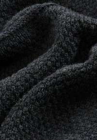 Tessuto lavorato a maglia grigio scuro con una superficie testurizzata e fuzzy, caratterizzato da una lavorazione allentata e variazioni nello spessore dei filati.