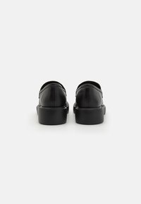 Mustad mustad nahast jalanõud ümarate kujunditega, millel on sile tekstuur ja paksud mustad tallad. Tagasiranne toob esile minimalistlikud õmblusdetailid.