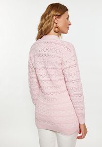 Pulover tricotat roz deschis, cu un design texturat cu modele în diamant, mâneci lungi și o margine cu nervuri.
