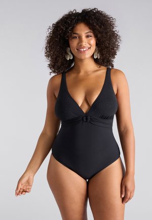 Maillot de bain une pièce noir avec un décolleté plongeant, texturé avec de petits clous et un détail de nœud à l'avant. Bretelles ajustables et jambes échancrées.