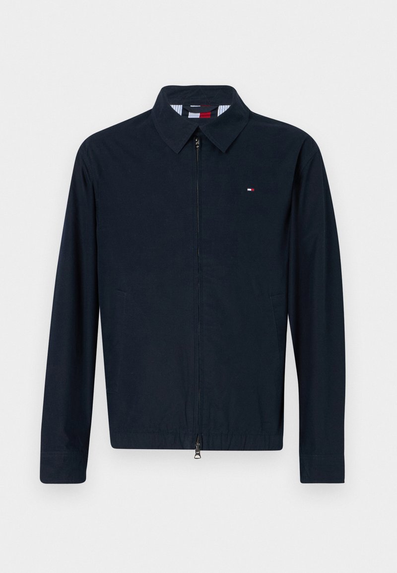 Marineblaues Jacket mit Reißverschluss vorne, mit umschlagenem Kragen und langen Ärmeln. Mit seitlichen Taschen und einem kleinen Logodetail auf der Brust. Glattes Material.