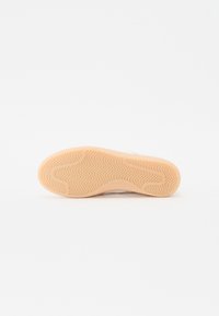 Sola di scarpe con un motivo testurizzato ondulato in gomma beige chiaro. Presenta un bordo liscio e una leggera curvatura verso l'area delle punte.