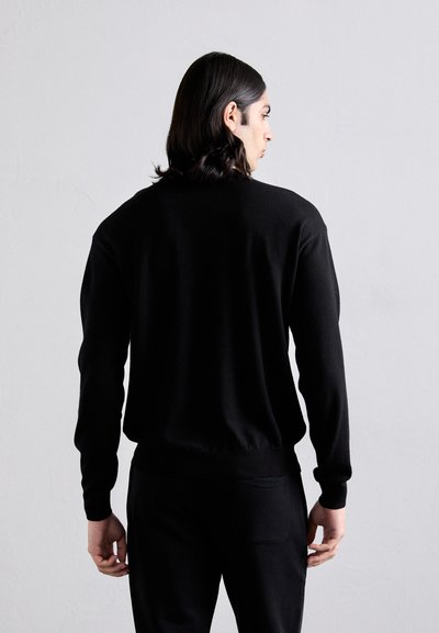 Suéter negro de punto con cuello redondo, mangas largas y puños y dobladillo acanalados. Presenta una textura suave y una silueta ajustada.