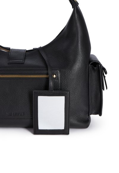 Borsa a mano in pelle nera con superficie texture, chiusura con zip dorata e portachiavi rimovibile. Presenta una forma curva e dettagli con nappine laterali.