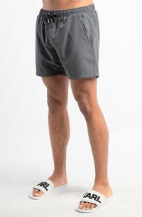 Grijze zwembroek met een elastische tailleband en verstelbaar koord, met zijzakken. Gecombineerd met witte slippers met de tekst 'PARL'.