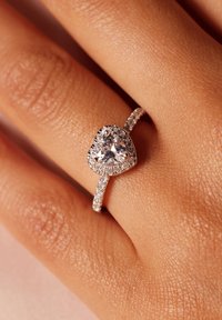Hartvormige heldere edelstenen ring met een sprankelende diamanten halo, voorzien van een delicate, dunne band versierd met kleinere diamanten.