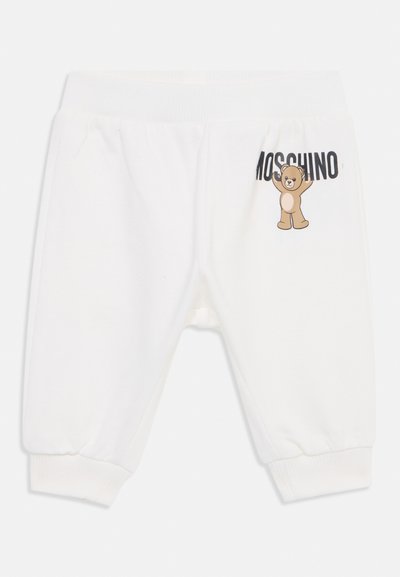 Joggers de algodón blanco con puños acanalados, que presentan un gráfico de un oso de dibujos animados y el texto "Moschino" impreso en negro en la parte frontal.