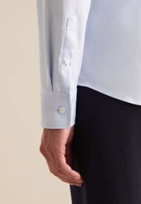 Lichtblauwe dresshirtmouw met knoopmanchetten, met een getextureerd diagonale patroon. De stof heeft een gladde afwerking en een getailleerd ontwerp.