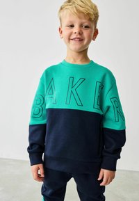 Grøn og marineblå sweatshirt med fed "BAKER" skrift, rund hals, lange ærmer og en lynlåslomme på siden. Blød struktur.