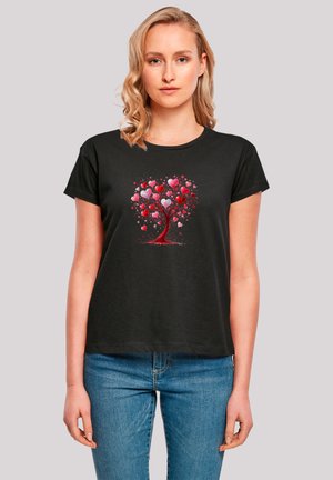 Schwarzes T-Shirt mit kurzen Ärmeln, das ein farbenfrohes Herzbaum-Motiv in Rot- und Rosatönen zeigt, vor einem schlichten Hintergrund.