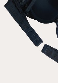 Sød marineblå bh med blonder, justerbare stropper og multi-krog lukning. Glat stoftekstur med bølgede kanter på stropperne.