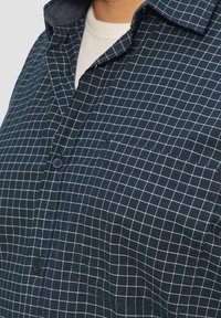 Heren button-down overhemd in marineblauw met wit ruitpatroon, enkele borstzak en een contrasterende kraag. Gemaakt van geweven stof.