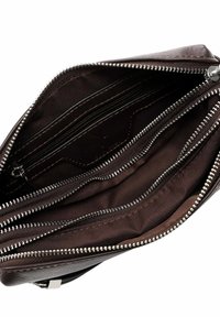 Interno di un portafoglio in pelle marrone con numerose tasche con zip, rivestimento in tessuto e accessori in argento. Le cerniere e le cuciture sono rifinite con cura.