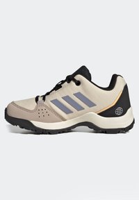 Baskets de sport beige et noires avec des rayures grises, tige en synthétique, tissu texturé, semelle en caoutchouc épaisse et détail unique du logo globe.