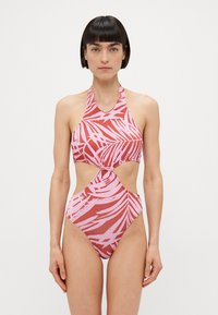 Eéndelige zwempak in roze en rood met palmbladprint, halternek en gedraaide voorkant. Heeft hoge uitsnijdingen bij de benen en een gladde textuur.