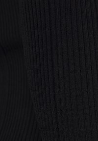 Primo piano di un tessuto nero a righe con linee testurizzate verticali in un motivo a maglia.