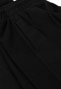 Zwarte sportshorts van zachte stof met een elastische tailleband, voorzien van plooien en gestructureerde details langs de naden.
