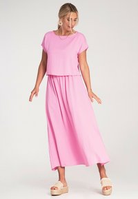 Różowa dwuczęściowa sukienka z krótkim topem i długą spódnicą, wykonana z lekkiego materiału. Luźny krój z opadającymi rękawami i luźną talią.